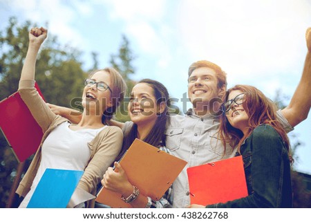 education, friendship, success and teenage concept - group of happy students showing triumph gesture at campus or park