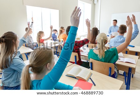 education, high school, teaching, learning and people concept - group of happy students raising hands and teacher in classroom