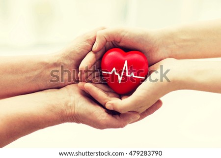 charity, health care, donation and medicine concept - man hand giving red heart with cardiogram to woman