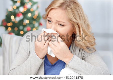 healthcare, flu, christmas, and people concept - ill woman blowing nose to paper napkin