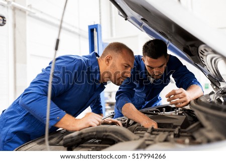 auto service, repair, maintenance and people concept - mechanic men with wrench repairing car engine at workshop