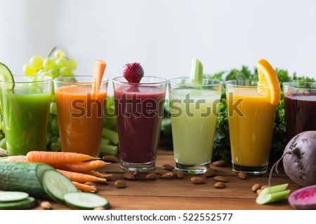 healthy eating, drinks, diet and detox concept - glasses with different fruit or vegetable juices and food on table