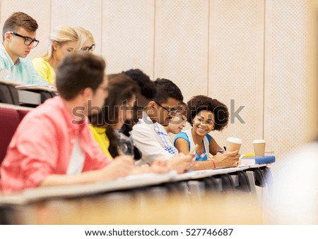 education, high school, university, learning and people concept - group of international students with notebooks and coffee writing test in lecture hall