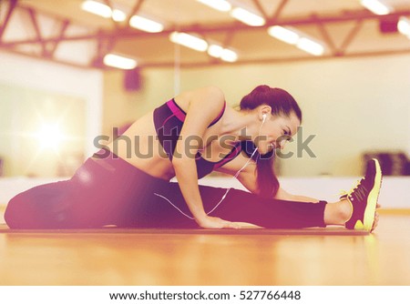 fitness, sport, training, gym and lifestyle concept - smiling woman stretching on mat in the gym