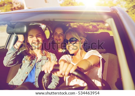 summer vacation, holidays, travel, road trip and people concept - happy teenage girls or young women driving in car
