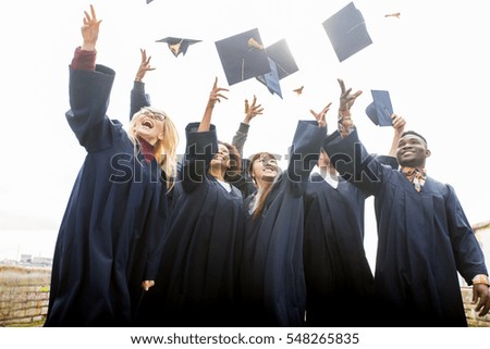 education, graduation and people concept - group of happy international students in bachelor gowns throwing mortar boards up