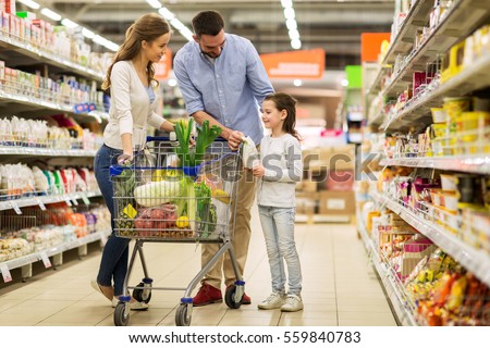 sale, consumerism and people concept - happy family with child and shopping cart buying food at grocery storeor supermarket