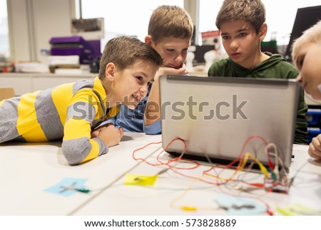 education, children, technology, science and people concept - group of happy kids with laptop computer playing with invention kit at robotics school lesson