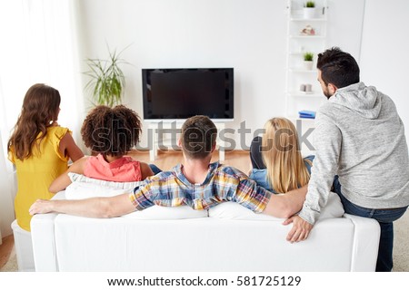 friendship, people and entertainment concept - happy friends watching tv at home