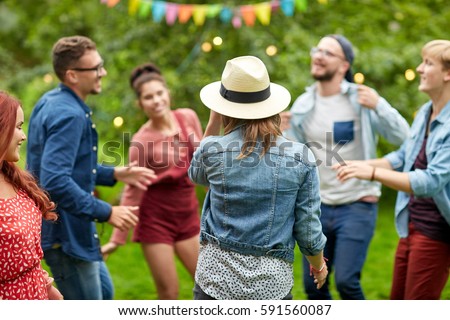 leisure, holidays, fun and people concept - happy friends dancing at summer party in garden