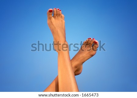 female legs and sandy feet over blue background