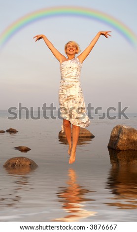lovely blond jumping in water under colorful rainbow