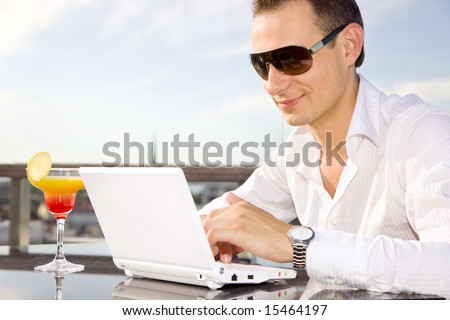 picture of handsome businessman on leisure with laptop and cocktail