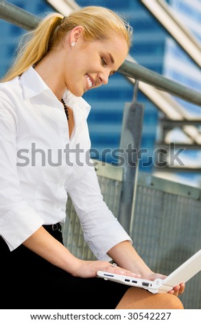 happy businesswoman with laptop computer in the city