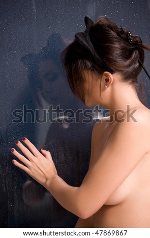 sad woman with cat ears at the rainy window (focus on reflection)