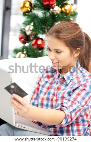 happy woman with laptop computer and credit card over christmas tree