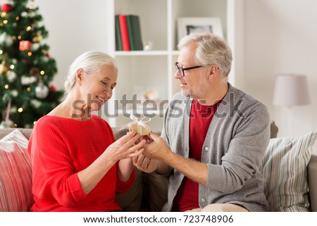 christmas, holidays and people concept - happy smiling senior couple with gift box at home