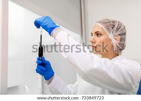 science, chemistry, industry and people concept - woman scientist or chemist with sulphuric acid in dropper at laboratory