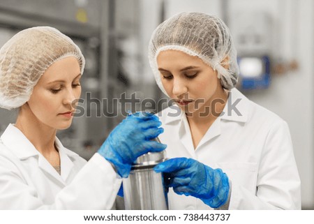 manufacture, industry, production and people concept - women technologists working at ice cream factory and assembling product dispenser together