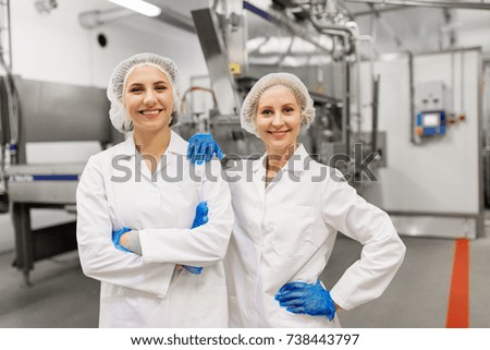 manufacture, industry and people concept - happy women technologists at ice cream factory shop