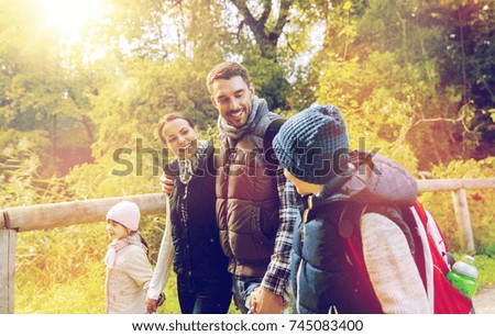travel, tourism, hike and people concept - happy family with backpacks hiking in woods