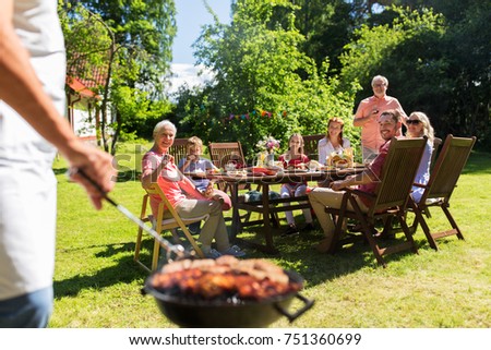 food, people and family time concept - man cooking meat on barbecue grill at summer garden party