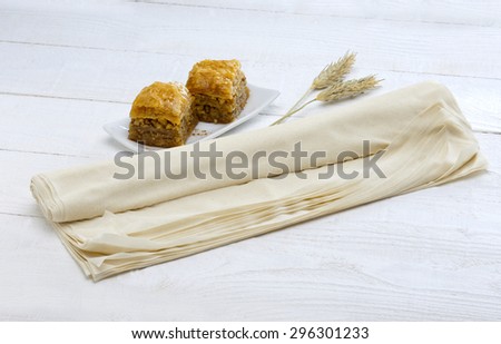 a roll of pastry or phyllo with two pieces of baklava served in a white plate(traditional oriental sweet)