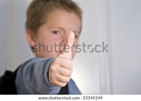 Young boy giving thumbs up with focus on thumb