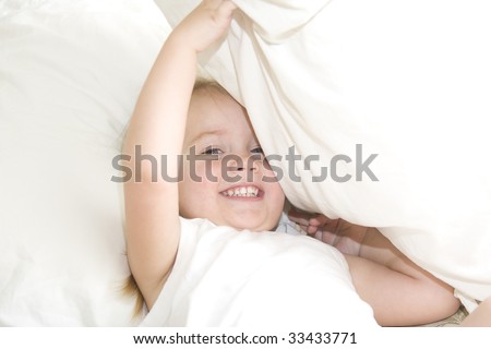 Baby girl playing peek a boo under pillow