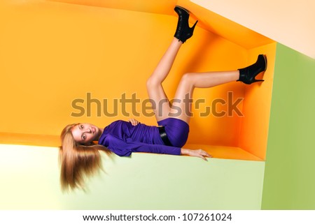 Portrait of a smiled crazy young woman lying in upside down posture