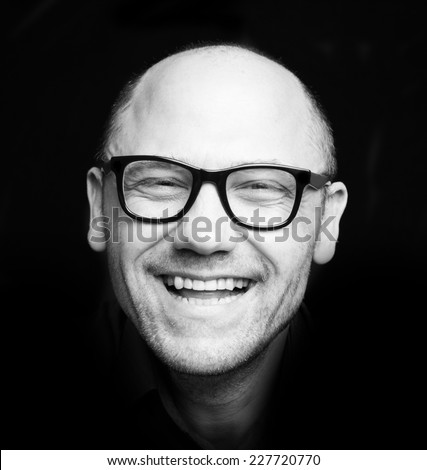 Close up black and white photo of laughing man in glasses.