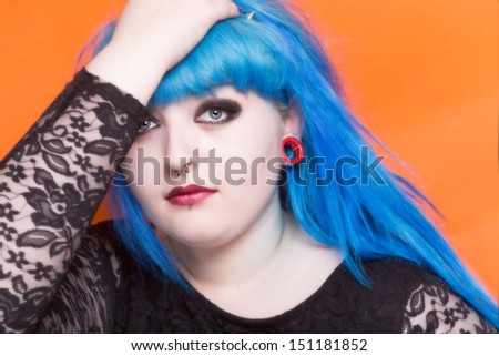 Beautiful young woman with blue hair and piercings looking at the camera