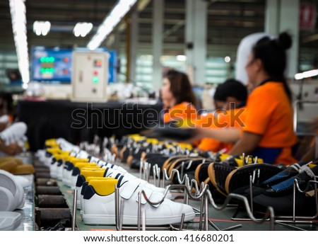 worker making sport shoe in footwear production line