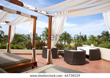 Outdoor cabana beds on a rooftop overlooking a tropical ocean.