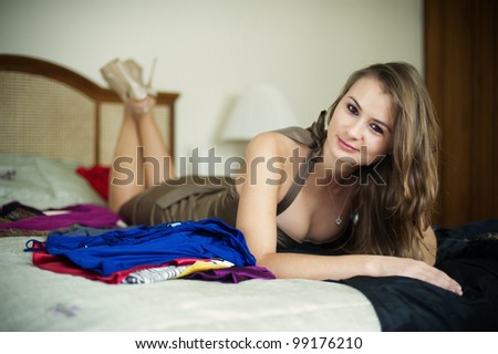 Young woman lying on bed with a pile of clothes.