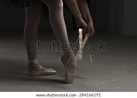 ballerina legs while tying ballet shoes