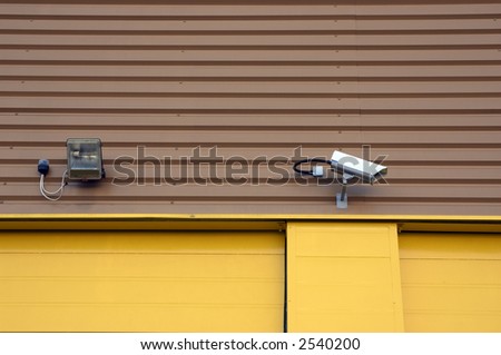 A security camera and a spot light on a warehouse