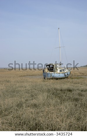 A small yacht in the mud at low tide