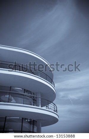 An Art-deco balcony against a blue sky toned blue