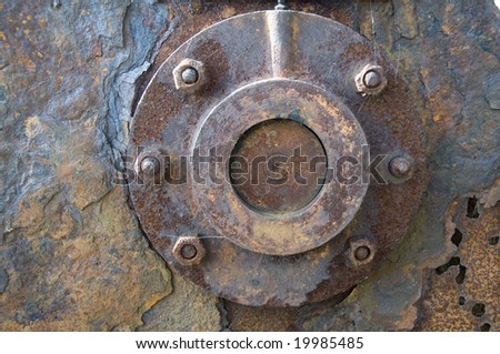 A piece of rusty metal with a round piece bolted to it