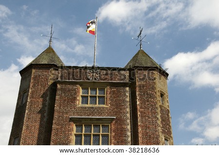A tower with turrets and a flag with a nice sky