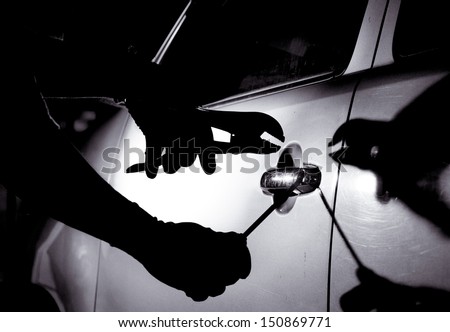Car thief using a tool to break into a car.
