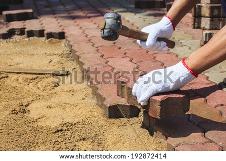 worker laying red concrete paving blocks.