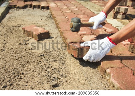 worker laying red concrete paving blocks.