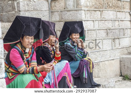 LIJIANG, CHINA - JUNE 21, 2015: A group of Yi Tribal Women dressed in traditional Clothes sell bracelets on the street. Located in Lijiang Old Town , Yunnan Province, China.