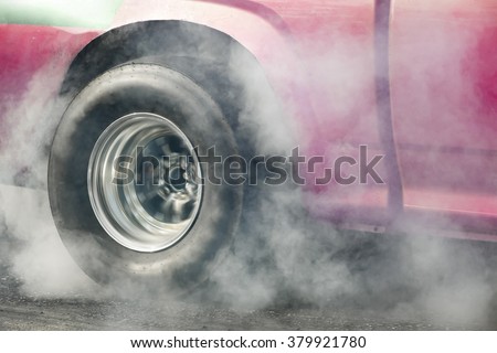 Drag racing car burns rubber off its tires in preparation for the race.