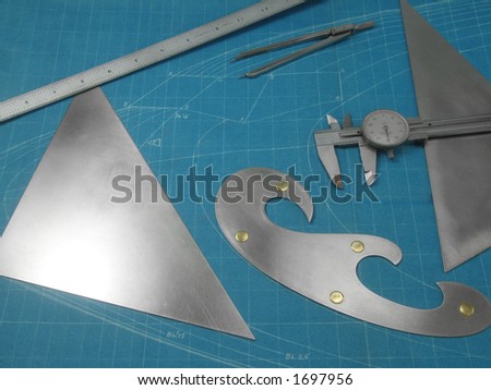 Custom machined, stainless steel drawing tools on a blueprint background. The blueprint is a training drawing of the nose contour of a large jet, no copyright, and over 50 years old.