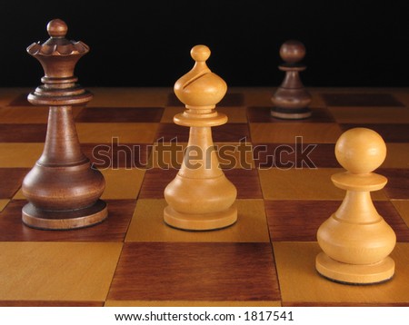 The black queen and white bishop of a wooden chess set in a standoff.