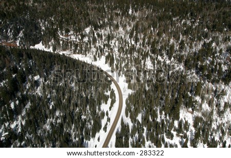 An aerial view of a road winding through a snow covered forest in Grand Canyon National Park.