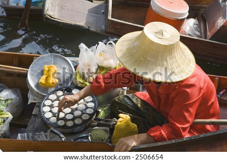Thai woman cooking and selling food at floating market near Bangkok, Thailand.